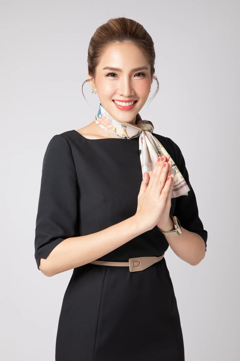 ครูเจนยิ้มต้อนรับและยกมือไหว้ ในชุดเดรสสีดำ